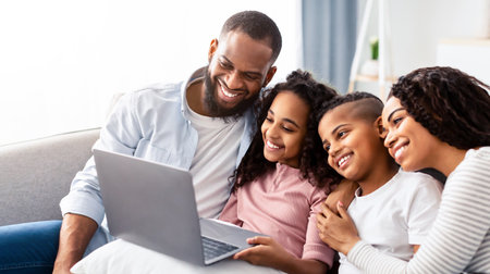 Happy african american family using laptop in living roomの写真素材