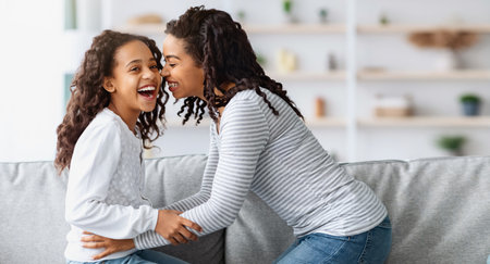 Happy african american mom tickling her laughing kidの写真素材