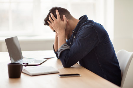 Exhausted arab man sitting in front of laptop, office interior