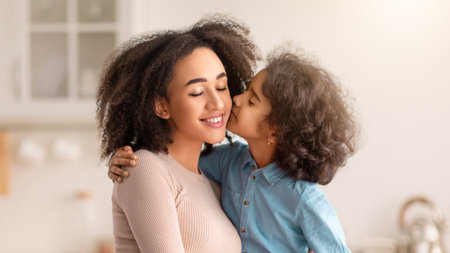 African American daughter hugging and kissing her smiling mumの写真素材