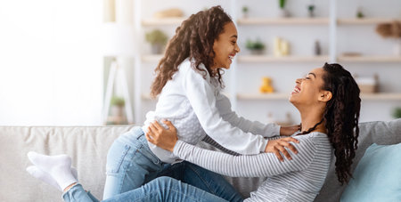 Loving black mother and kid bonding while relaxing on couchの写真素材