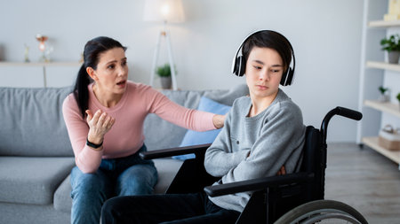 Depression in disabled teens. Sad adolescent in wheelchair shutting himself off from world, mother...