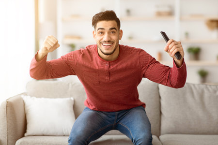 Happy arab guy watching sport on TV at home