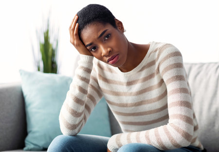 Portrait Of Upset Black Female Sitting On Couch And Looking At Cameraの写真素材