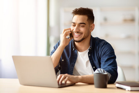 Successful middle-eastern guy talking on phone while working at home