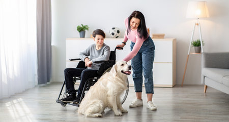 Young mother and her handicapped son in wheelchair playing with their dog at homeの写真素材