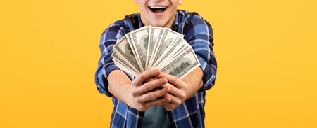 Unrecognizable young guy holding fan of money, winning lottery on orange studio background, closeup...