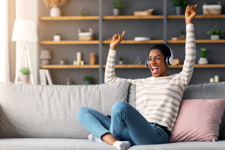 Favorite Song. Cheerful Young Black Woman Listening Music In Headphones At Homeの写真素材