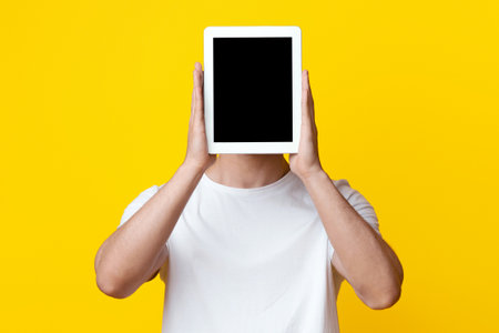 Unrecognizable guy hiding behind digital tablet with blank screen