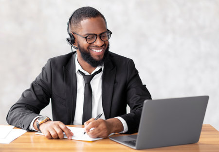 African American man using laptop writing in notebook
