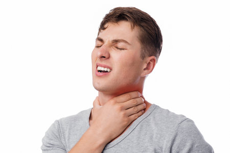 Upset attractive young european guy suffer from sore throat and pressing hand to sore spot, with...