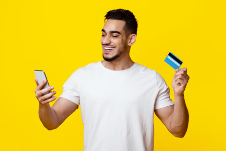 Positive middle eastern guy with smartphone and credit card