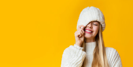 Carefree girl covering her eye with white knitted hat