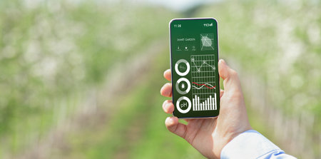 Farmer holding cellphone with smart gardening data on screen, monitoring soil ph, temperature,...