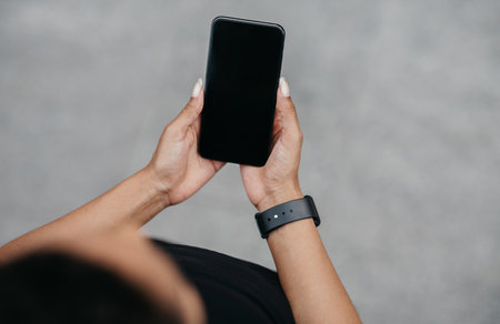 Sport blog and followers. African american girl with fitness tracker holding smartphone with blank...