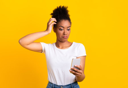 Confused young african woman using mobile phone