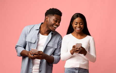 Cheerful african american couple using their newest cellphones