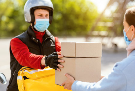Courier In Medical Mask Giving Lunch Boxes To Girl Outdoor
