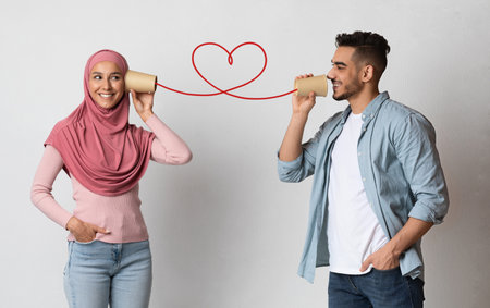 Romantic guy sending love message to muslim girlfriend through paper cup phone