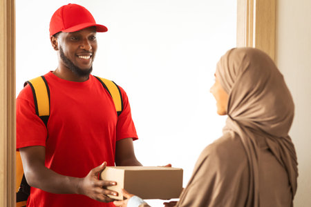Black delivery man holding box giving it to muslim customer