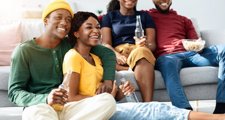 Joyful african american friends watching movie, sitting on floor