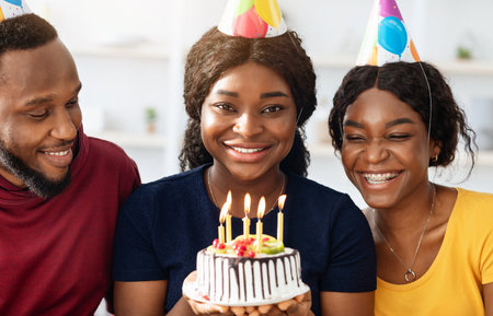 Pretty black birthday lady holding cake with lit candles