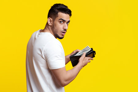 Shocked middle eastern guy holding wallet with money