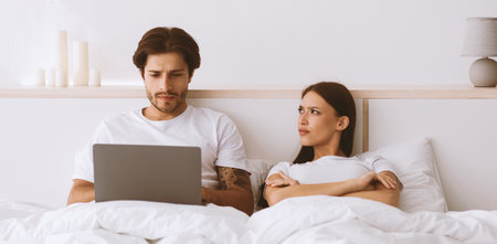 Pretty millennial european lady looking at husband, guy working on laptopの写真素材