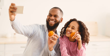 Cheerful black father taking selfie with cute daughter