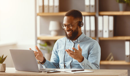 Smiling young black bearded male in glasses and headphones gestures, communication and works