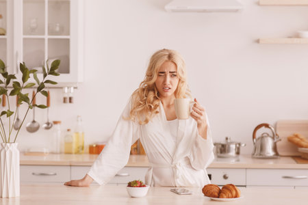 Tired sleepy woman eating breakfast alone, facial emotions, insomnia and sleeping disorderの写真素材