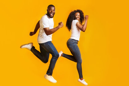 Joyful afro man and woman are running in the airの写真素材