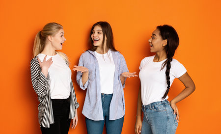 Excited teen girls talking and gossiping over backgroundの写真素材