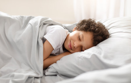 Young African American Boy Sleeping in Bedの写真素材