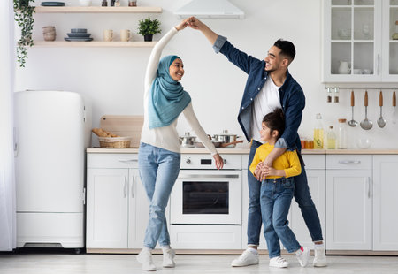 Domestic Fun. Happy Middle Eastern Family Of Three Dancing In Kitchen Togetherの写真素材