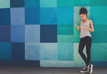 African-american woman posing, leaning on bright wallの写真素材