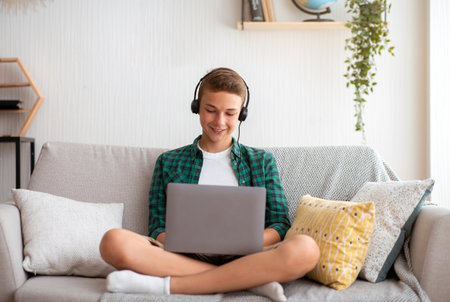 Happy school boy with headset playing games on laptop