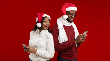 Black Girlfriend Looking At Boyfriends Phone Wearing Santa Hats, Studio