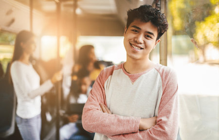 Happy Teenager Smiles Confidently on a Bus During a Sunny Afternoon Ride With Friendsの写真素材