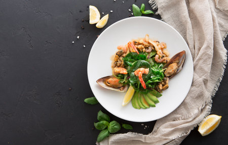 Seafood dish with shrimp, mussels, and fresh greens on a dark tableの写真素材