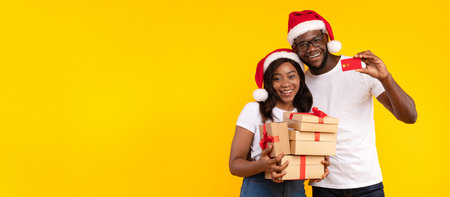 African Couple Showing Credit Card Holding Christmas Gifts, Yellow Backgroundの写真素材