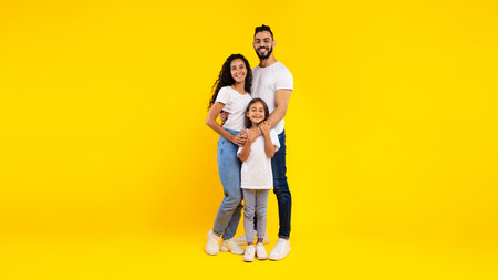 Full-Length Shot Of Middle-Eastern Family Hugging Standing On Yellow Background
