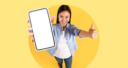 Happy Woman Showing Smartphone in a Studio With Yellow Background and Expressing Excitement