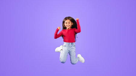 Little Girl Jumping Having Fun Posing In Mid-Air, Blue Backgroundの写真素材