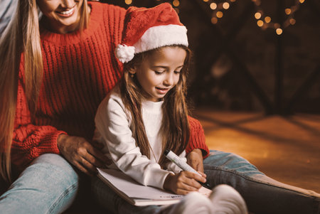 Portrait of happy woman and daughter writing letter to Santaの写真素材