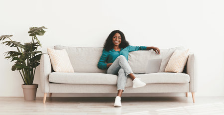 Joyful african american woman relaxing on couch at home