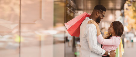 Happy afro couple hugging and holding shopping bagsの写真素材