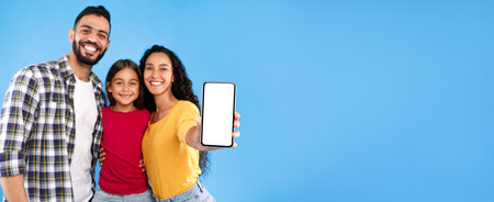 Family Showing Cellphone Screen To Camera Over Blue Background