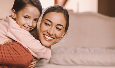 Portrait of happy woman and daughter hugging at homeの写真素材