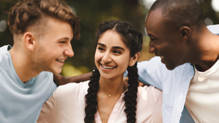 Portrait of cheerful multiracial college students walking outdoors after passing exam, embracing and sincerely laughing,の写真素材